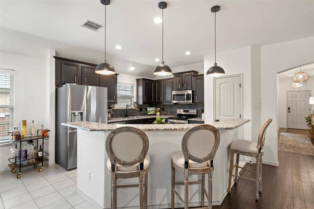 2189 Liriope Lane, Waxahachie, TX 75165 The kitchen combines granite countertops, dark cabinetry and stainless steel appliances with a NEW BACKSPLASH, UPDATED FIXTURES and MODERN LIGHTING for a refreshed, current look.