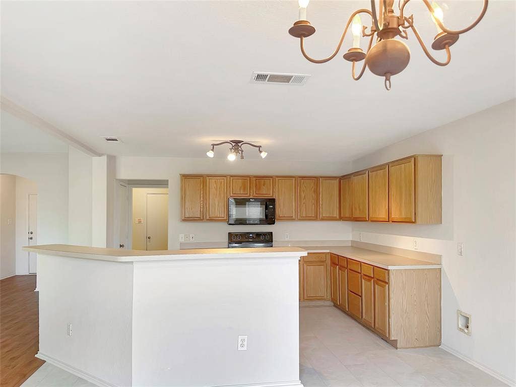 3457 Newgate Street, Midlothian, TX 76065 Kitchen with black appliances, a chandelier, arched walkways, light countertops, and bar