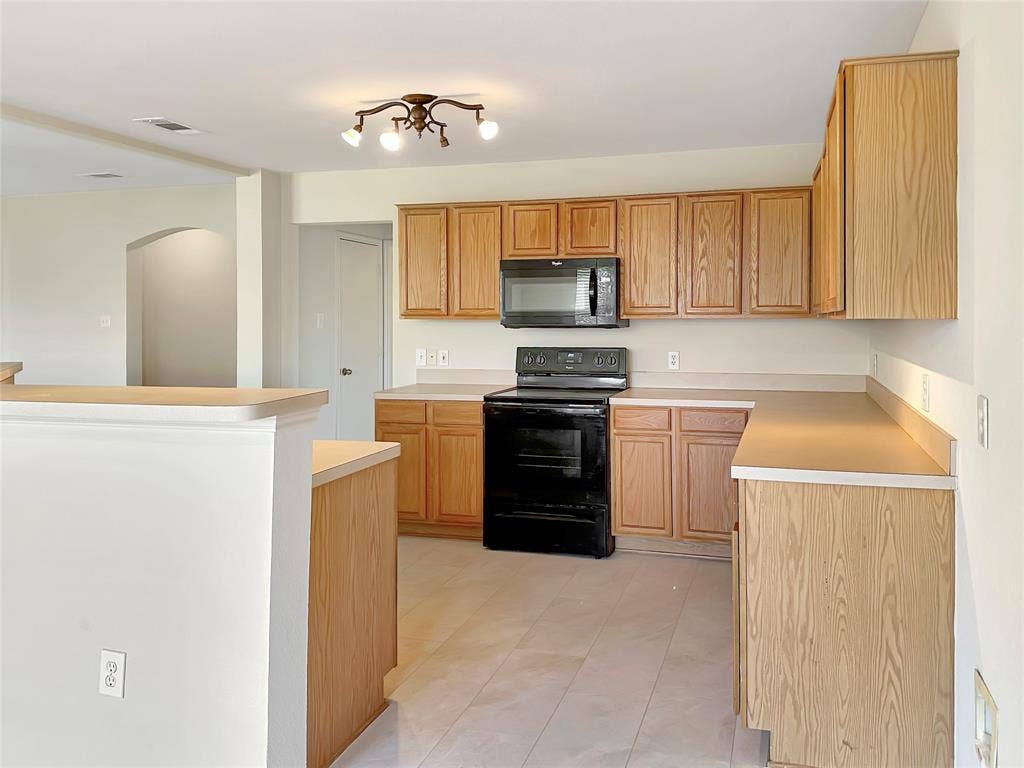 3457 Newgate Street, Midlothian, TX 76065 Kitchen featuring black appliances, light countertops, arched walkways, and light tile patterned flooring