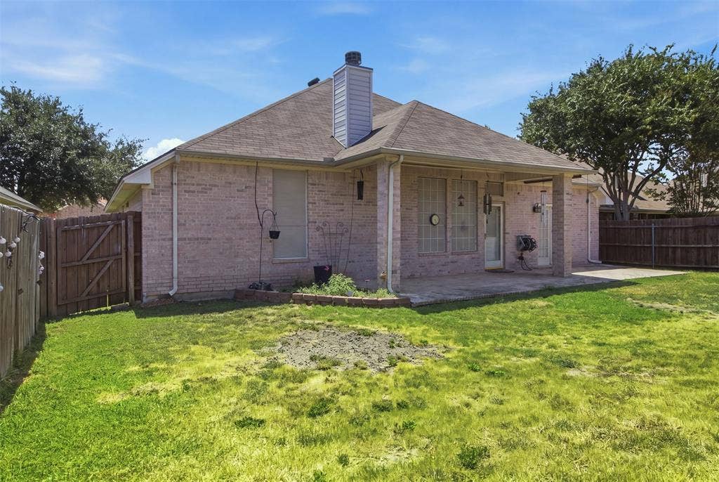1112 Badbury Lane, Grand Prairie, TX 75052 Rear exterior featuring brick facade, covered patio, concrete patio extension, and fenced perimeter