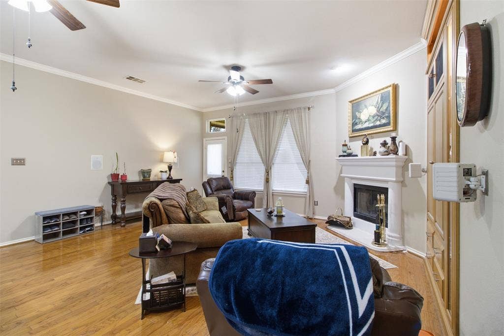 1112 Badbury Lane, Grand Prairie, TX 75052 Living space featuring wood flooring, a fireplace with a mantel, crown molding, and ceiling fans