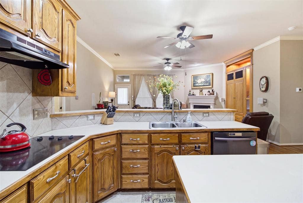 1112 Badbury Lane, Grand Prairie, TX 75052 Wood-finish cabinetry, built-in electric cooktop, stainless steel double basin sink, tile backsplash, and overhead range hood