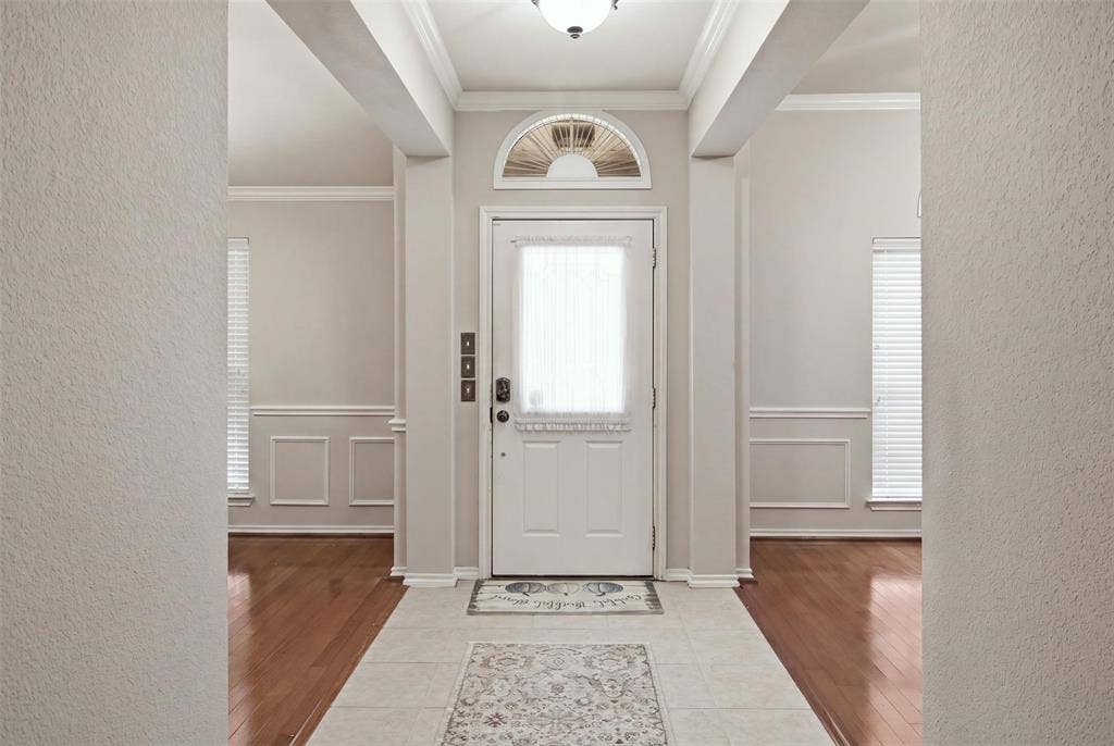 1112 Badbury Lane, Grand Prairie, TX 75052 Entryway featuring a decorative transom window, overhead flush mount light, tile flooring, and wood-finish flooring