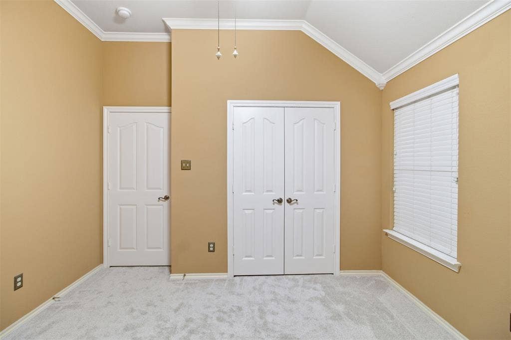 1112 Badbury Lane, Grand Prairie, TX 75052 Vaulted ceiling with crown molding, double bifold closet doors, and light-colored carpeting