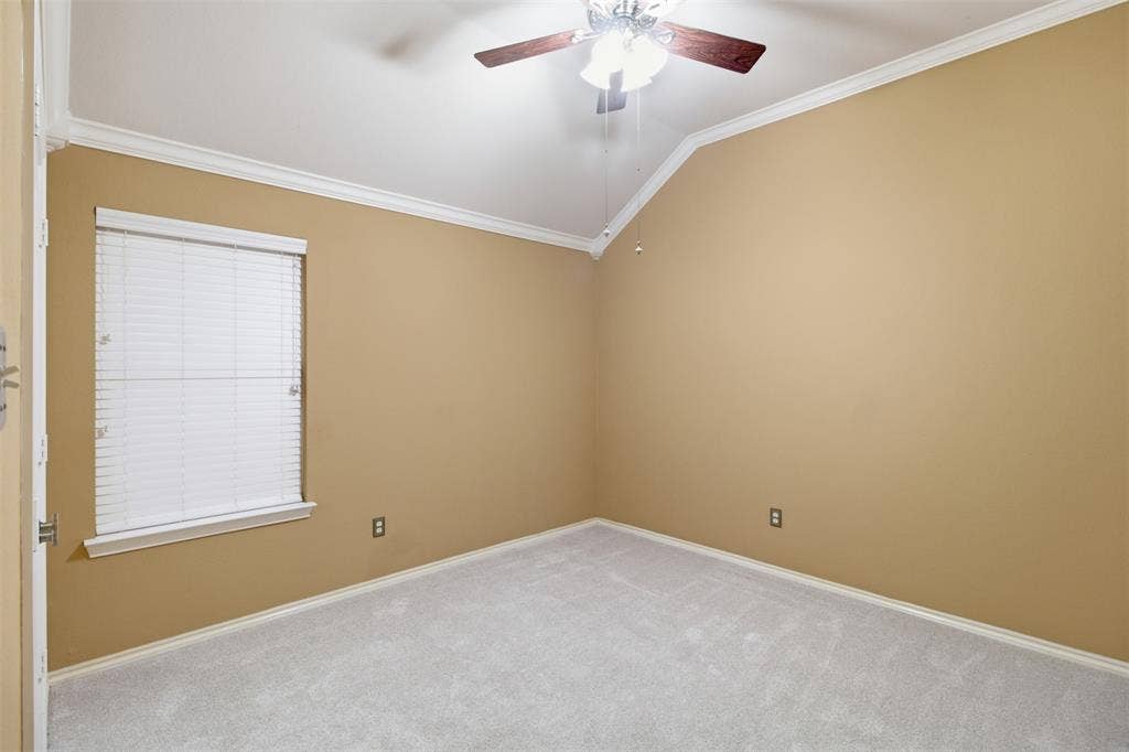 1112 Badbury Lane, Grand Prairie, TX 75052 Vaulted ceiling with a ceiling fan, crown molding, light-colored carpeting, and a window with blinds