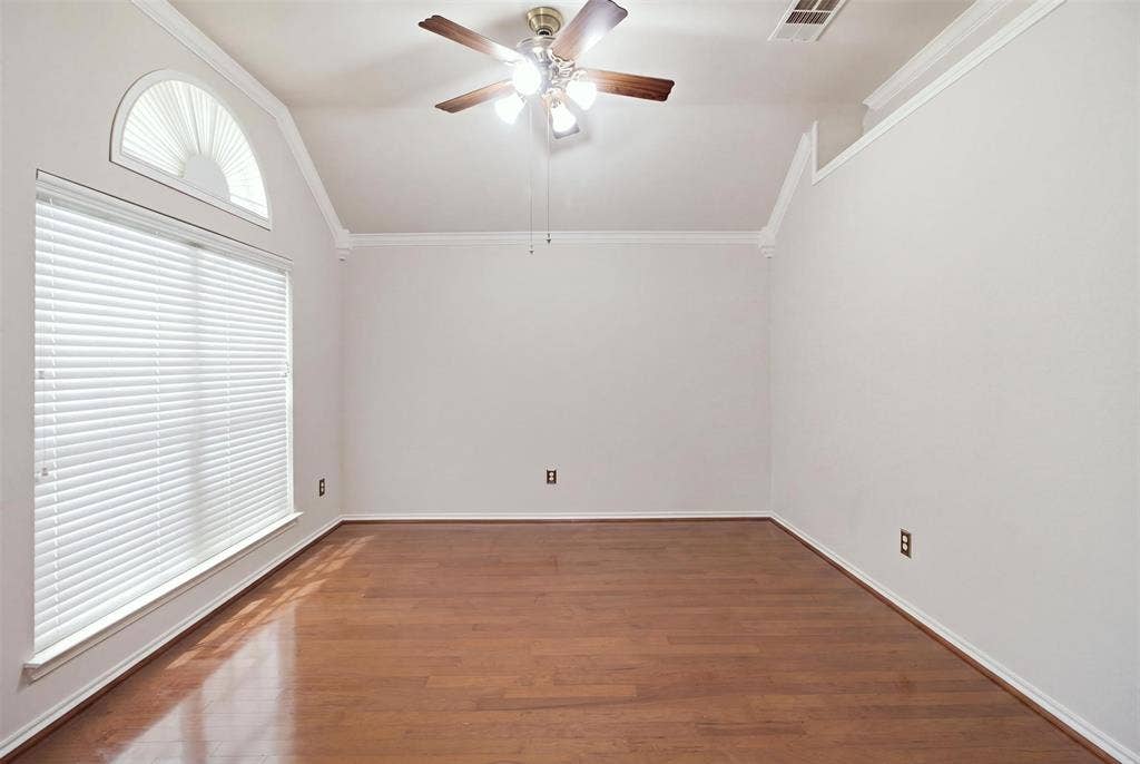 1112 Badbury Lane, Grand Prairie, TX 75052 Vaulted ceiling with crown molding, wood-finish flooring, large window with blinds, and an arched transom window