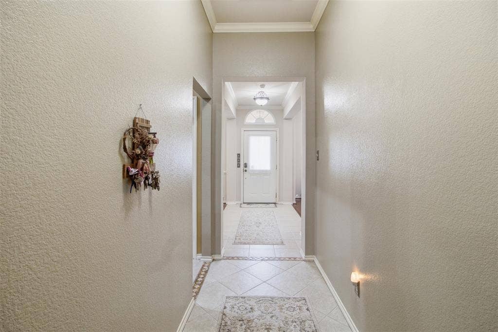 1112 Badbury Lane, Grand Prairie, TX 75052 Hallway featuring light-toned textured walls, crown molding, and decorative tile flooring