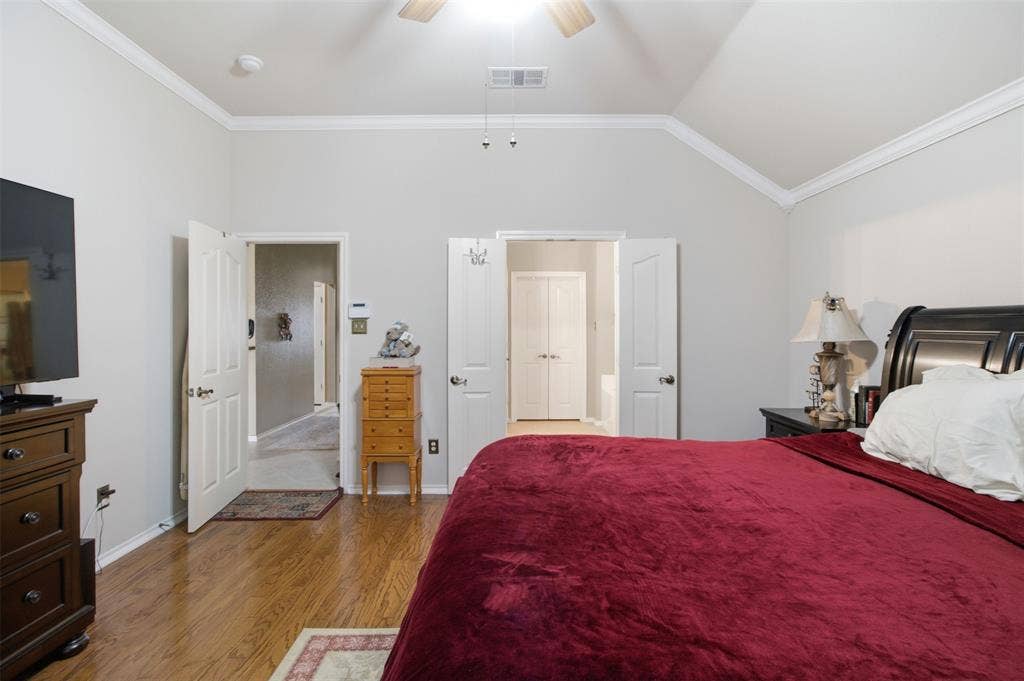 1112 Badbury Lane, Grand Prairie, TX 75052 Vaulted ceiling with a ceiling fan, crown molding, wood-finish flooring, and white paneled doors