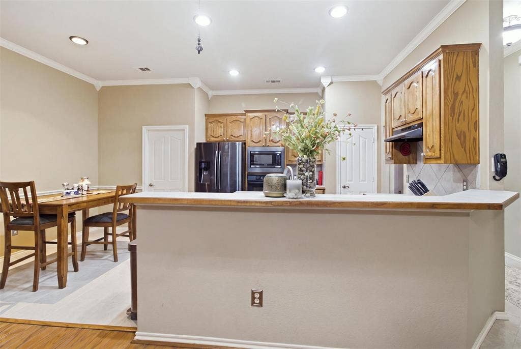 1112 Badbury Lane, Grand Prairie, TX 75052 Kitchen featuring wood cabinetry, integrated appliances, and a breakfast bar