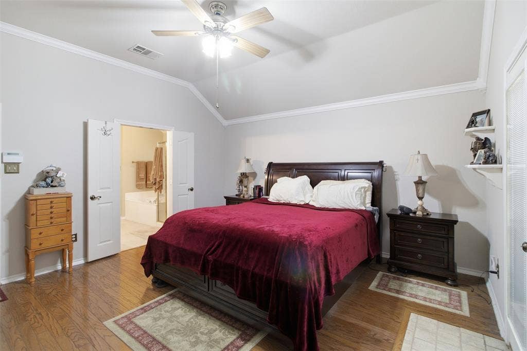 1112 Badbury Lane, Grand Prairie, TX 75052 Vaulted ceiling with crown molding, wood-finish flooring, ceiling fan with integrated lighting, and double doors to a separate bathroom featuring a built-in tub