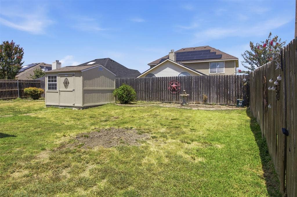 1112 Badbury Lane, Grand Prairie, TX 75052 Expansive backyard featuring a wood-panel fence and a detached storage shed with a single window