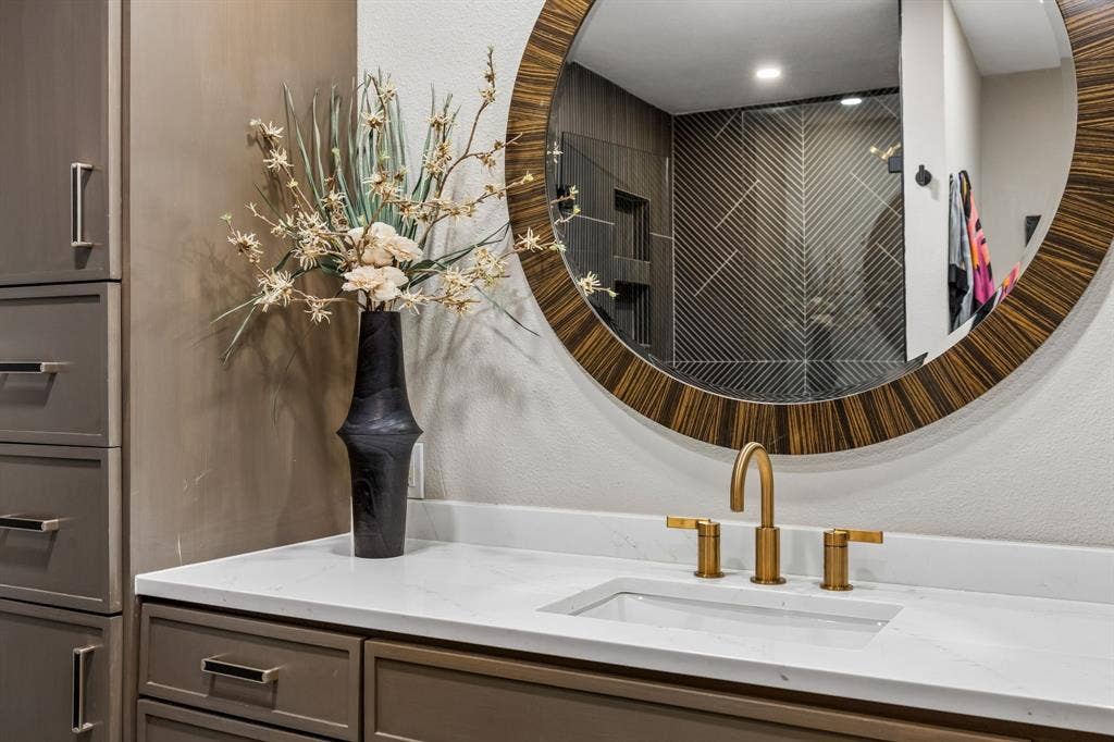 White quartz countertop with an undermount sink and a brass-finish faucet