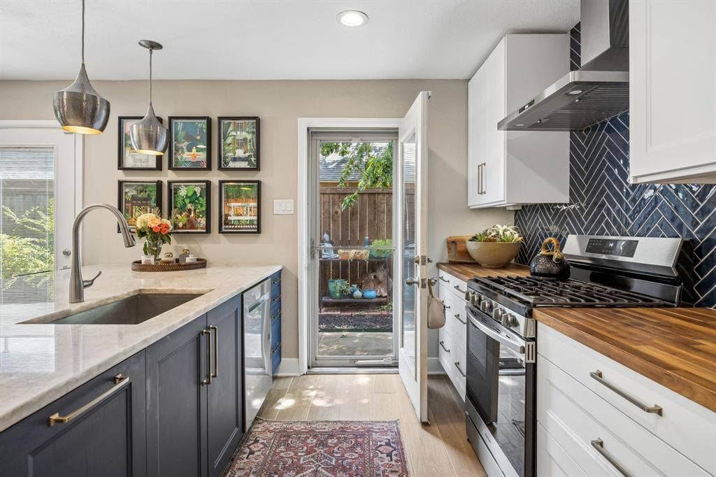 Kitchen featuring two-tone cabinetry, quartzite countertops, a herringbone tile backsplash, wood countertops, and stainless steel appliances