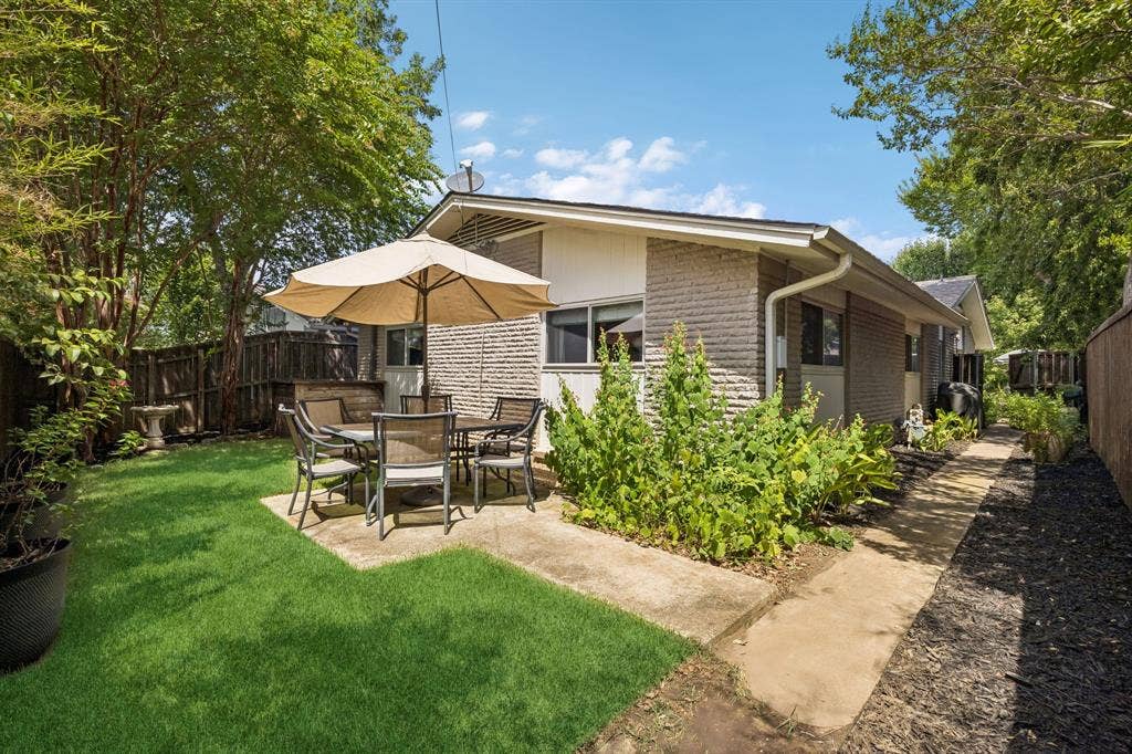 Expansive backyard featuring a manicured lawn, concrete patio, and a privacy fence