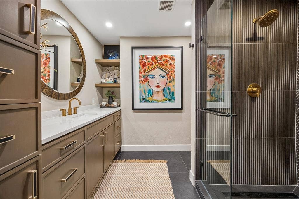 Built-in vanity with a white quartz countertop and gold-finish fixtures