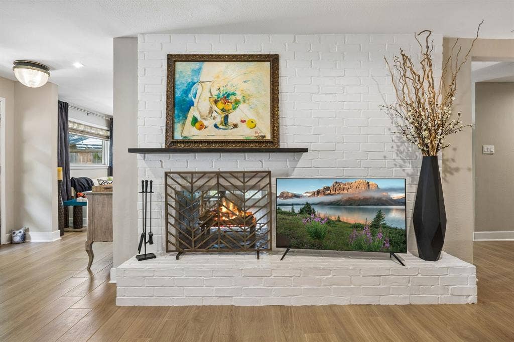 Painted brick fireplace with a decorative metal screen, a dark mantel, and tile flooring