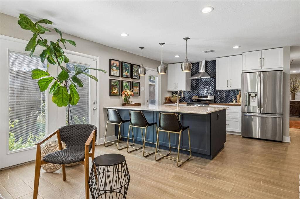 Gourmet kitchen featuring a large island, stainless steel appliances, herringbone tile backsplash, recessed lighting, and tile flooring