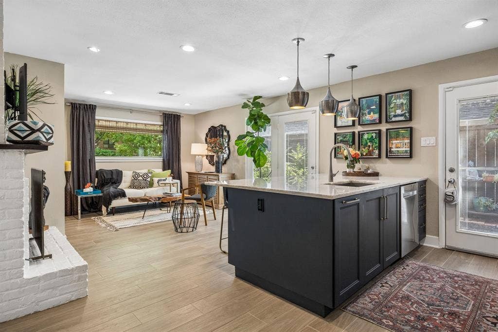 Open-concept living space with wood-finish flooring, a white brick see through fireplace, and recessed lighting