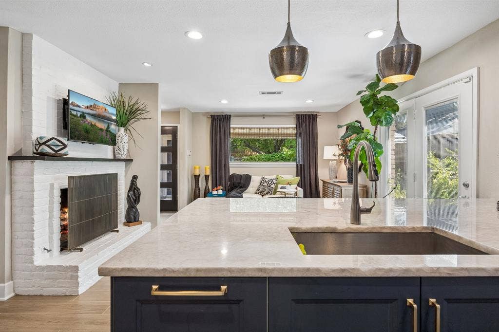 Kitchen island with quartzite countertop, deep sink, and dark cabinetry with gold-toned hardware