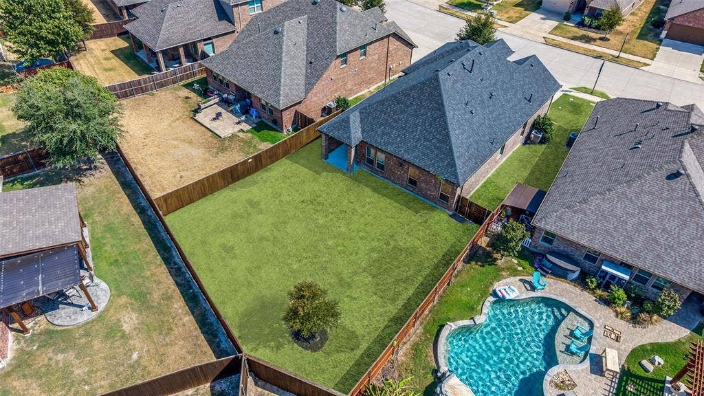 Expansive fenced backyard featuring a manicured lawn and a single ornamental tree