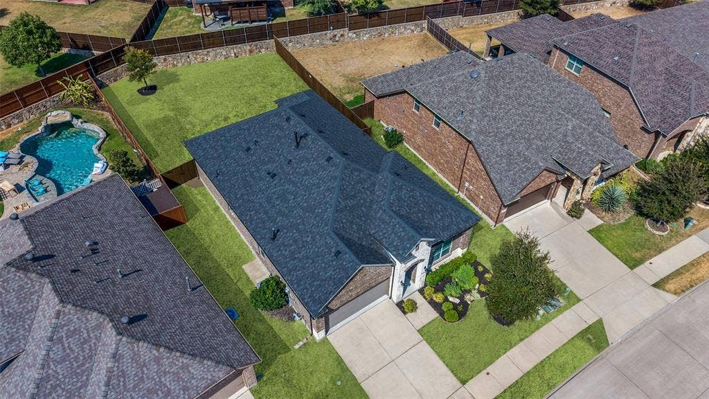 Exterior brick and stone facade, attached two-car garage, established front landscaping, fenced backyard, and paved driveway