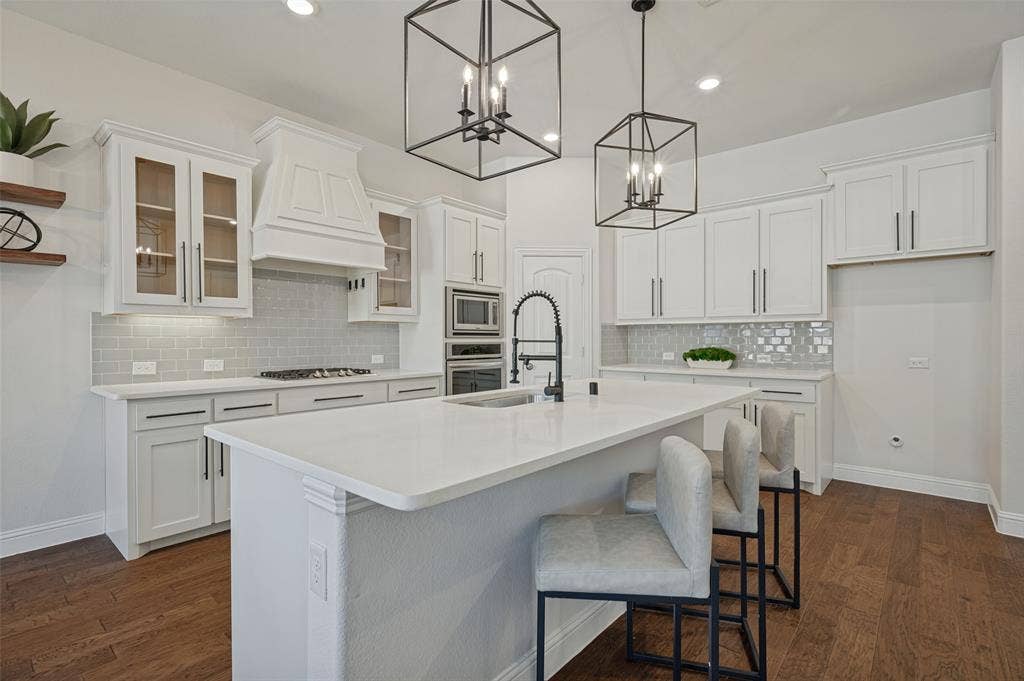 Kitchen featuring a large central island, white cabinetry, wood-finish flooring, subway tile backsplash, and recessed lighting