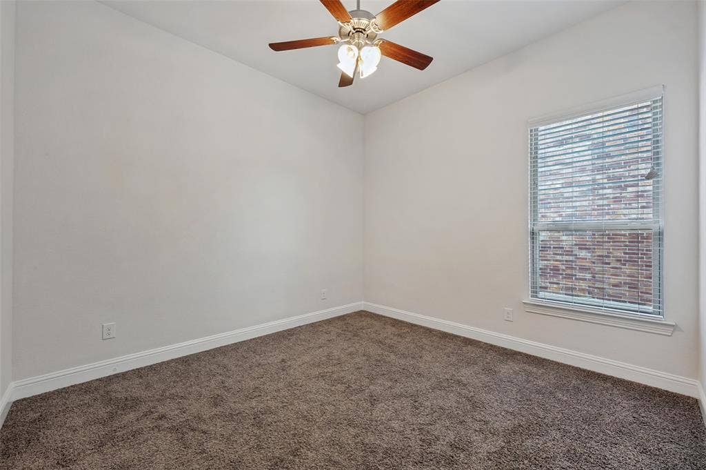 Neutral wall color, carpeted flooring, window with blinds, and a ceiling fan with integrated lighting