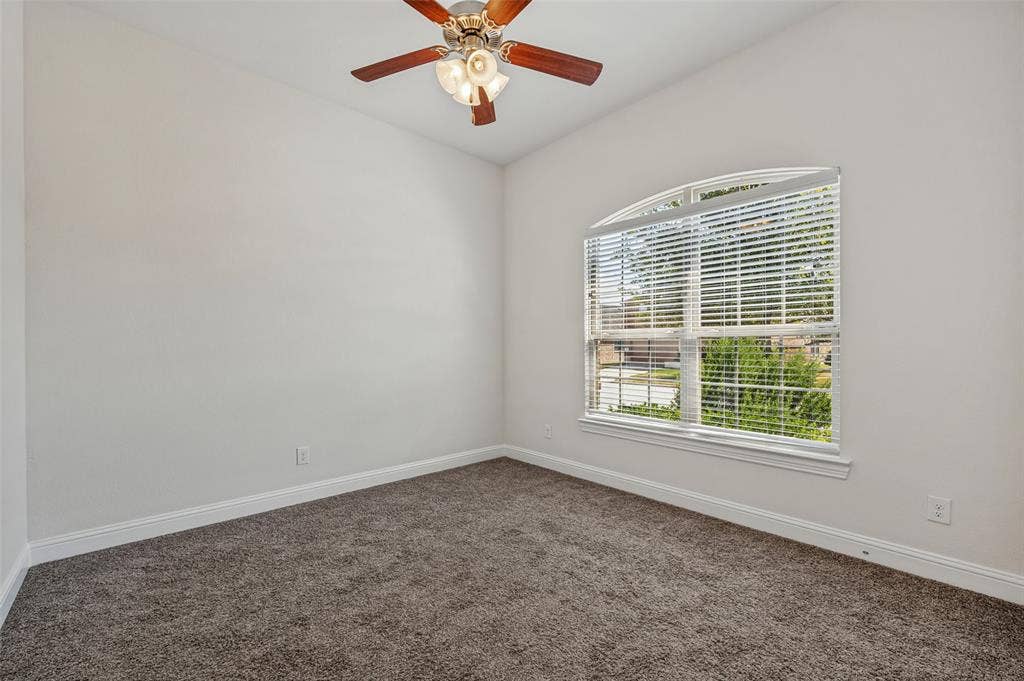Vaulted ceiling with a wood-finish ceiling fan, arched window with horizontal blinds, and carpeting