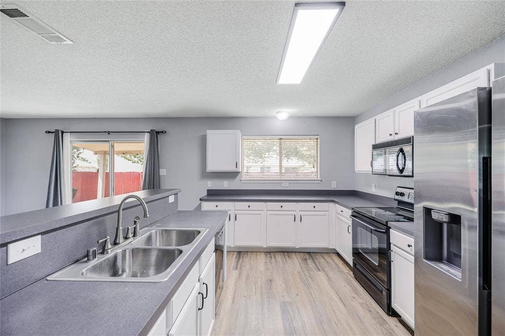 117 Palomino Lane, Krum, TX 76249 Stainless sink, built-in microwave, glass top range, and a stainless refrigerator featured in this well laid out kitchen