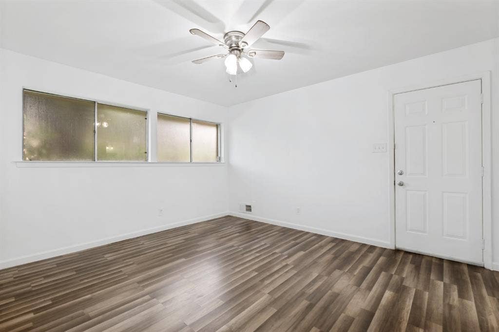4315 Woodstock Drive, Dallas, TX 75232 Wood-finish flooring, white walls, multiple windows, white paneled door, and a ceiling fan