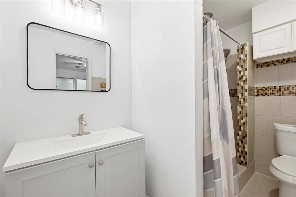 4315 Woodstock Drive, Dallas, TX 75232 Clean and functional bathroom featuring a white vanity with dual cabinet storage, rectangular sink, and brushed nickel faucet