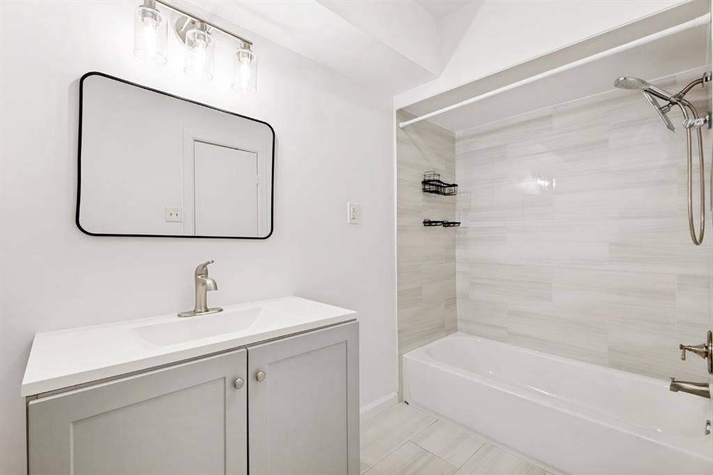 4315 Woodstock Drive, Dallas, TX 75232 White vanity with a single basin sink, brushed nickel faucet, and a black framed rectangular mirror