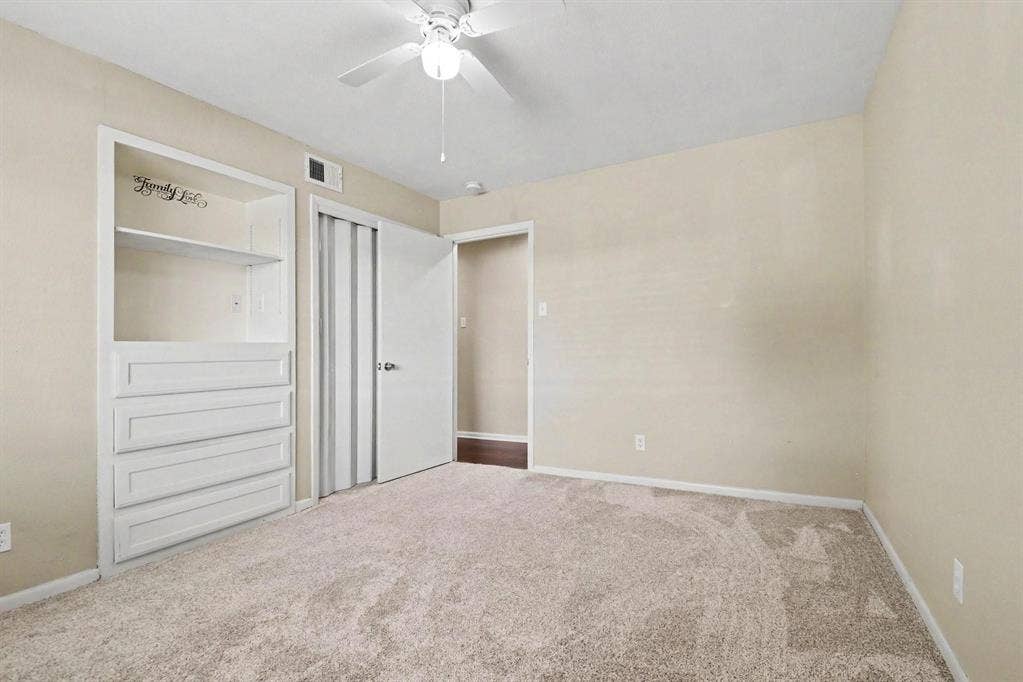 1114 Glouchester Drive, Garland, TX 75040 Built-in shelving and dresser unit, ceiling fan with light fixture, carpeted flooring, and a sliding closet door