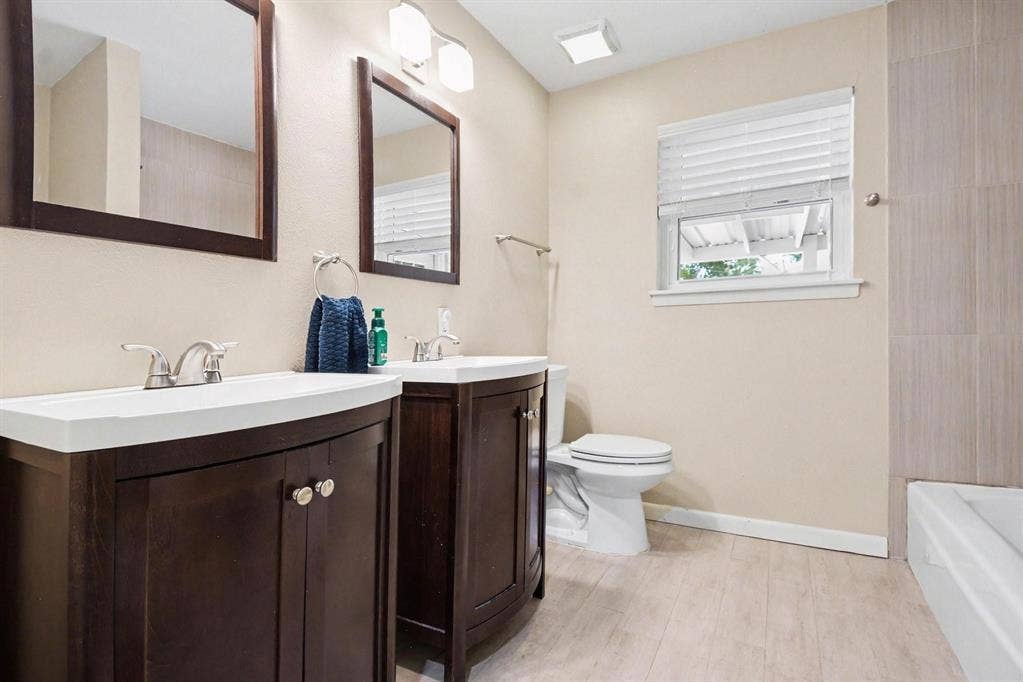 1114 Glouchester Drive, Garland, TX 75040 Dual wood-finish vanities with integrated sinks, brushed nickel faucets, and coordinating framed mirrors
