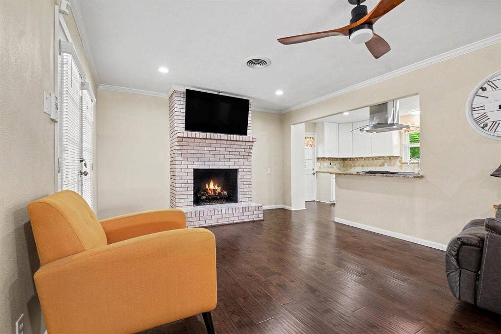 1114 Glouchester Drive, Garland, TX 75040 Hardwood flooring, brick fireplace, recessed lighting, ceiling fan, and a kitchen pass-through with stone countertops