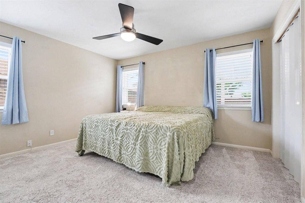 1114 Glouchester Drive, Garland, TX 75040 Neutral wall color, ceiling fan with integrated lighting, two windows with blinds, and light-colored carpeting
