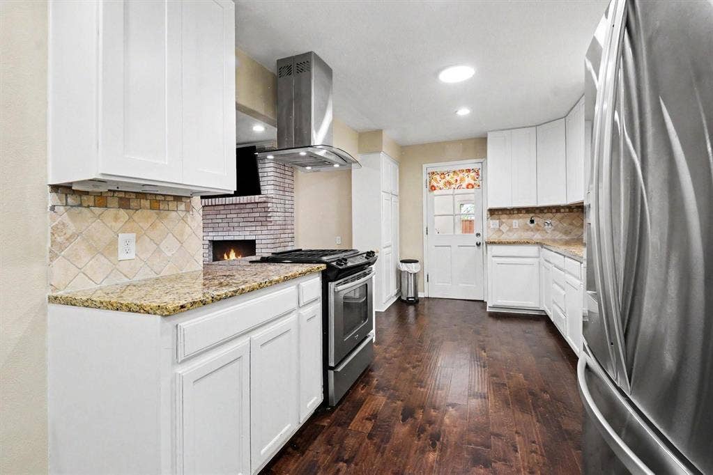 1114 Glouchester Drive, Garland, TX 75040 Kitchen featuring white cabinetry, granite countertops, tile backsplash, stainless steel appliances, and wood-finish flooring