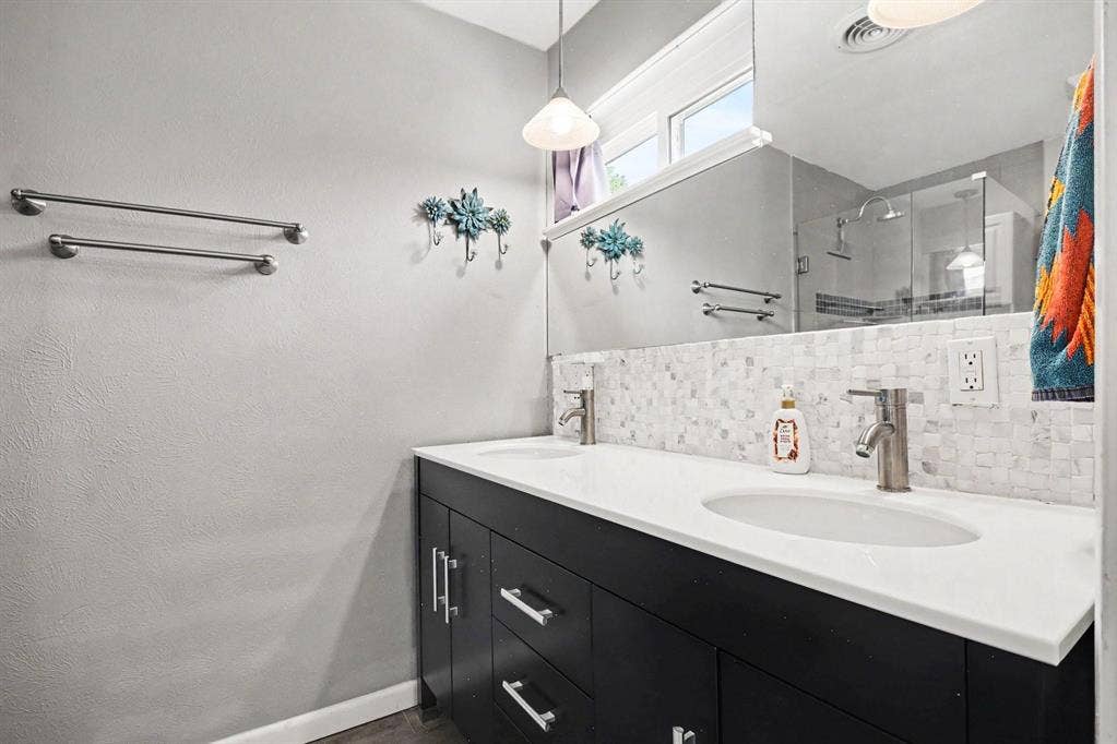 1114 Glouchester Drive, Garland, TX 75040 Dual vanity with white countertop, undermount sinks, and a mosaic tile backsplash