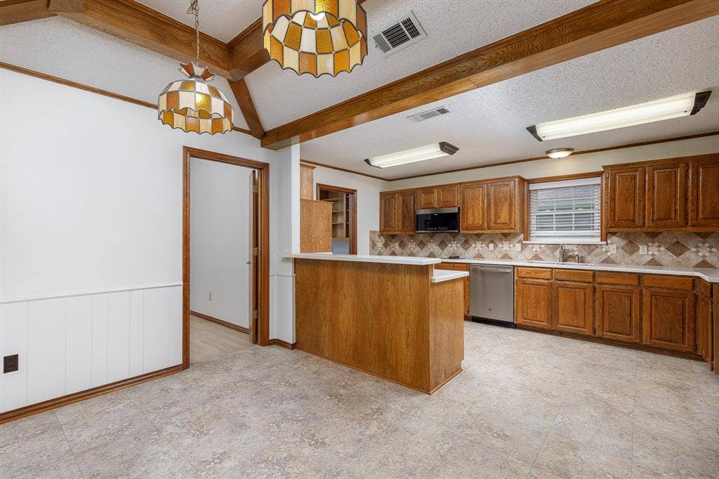 2526 Willowdale Drive, Carrollton, TX 75006 Kitchen with wood cabinetry, stainless steel appliances, and a breakfast bar