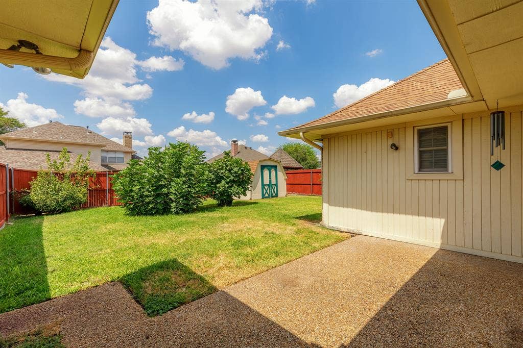 2526 Willowdale Drive, Carrollton, TX 75006 Expansive backyard featuring a manicured lawn, established shrubbery, a storage shed, and a privacy fence