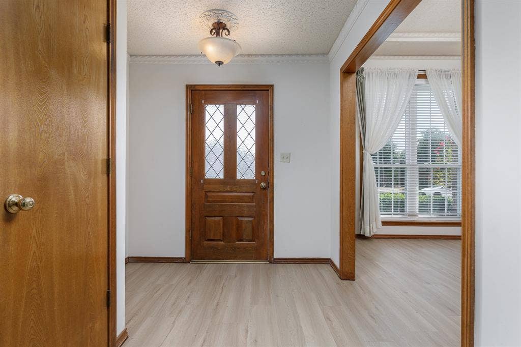 2526 Willowdale Drive, Carrollton, TX 75006 Entryway featuring wood-finish flooring, decorative ceiling fixture, and a solid wood entry door with leaded glass