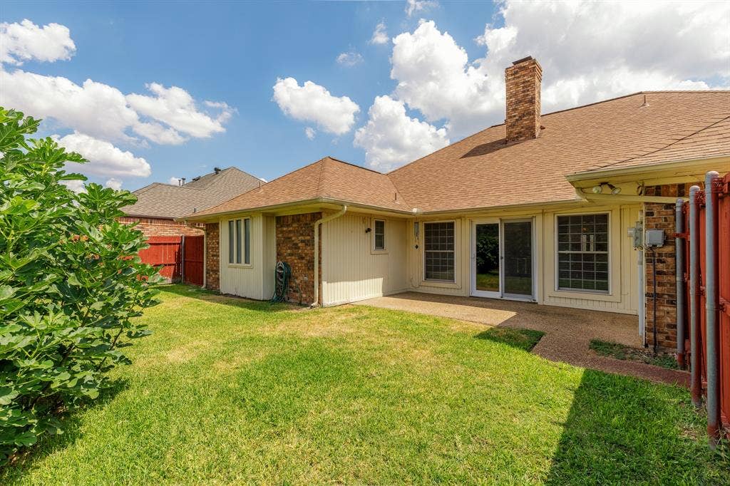 2526 Willowdale Drive, Carrollton, TX 75006 Expansive green lawn, brick exterior, composition shingle roof, sliding glass doors, and a stone chimney