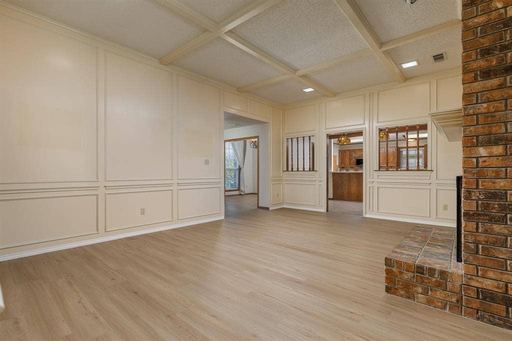 2526 Willowdale Drive, Carrollton, TX 75006 Wood-finish flooring, brick-clad fireplace with hearth, coffered ceiling, and wainscoting paneling