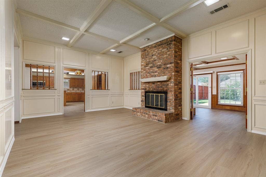 2526 Willowdale Drive, Carrollton, TX 75006 Brick fireplace with a white mantel, wood-finish flooring, and paneled walls