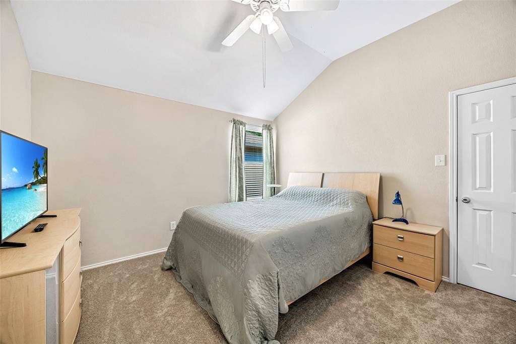 Vaulted ceiling, ceiling fan, carpet flooring, window with blinds, and paneled door