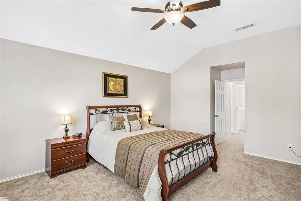Vaulted ceiling with an attached ceiling fan, neutral carpet, and a paneled interior door
