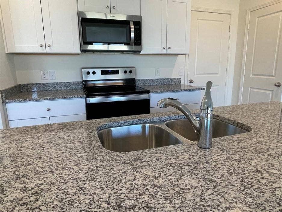 1903 Marquette Drive, Princeton, TX 75407 Kitchen featuring granite countertops, stainless steel appliances, white cabinetry, a dual-basin sink, and a pull-down faucet