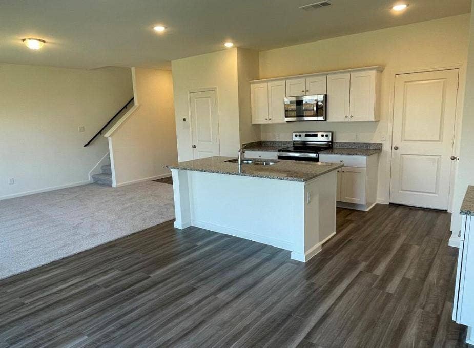 1903 Marquette Drive, Princeton, TX 75407 Kitchen featuring a central island, white cabinetry, integrated stainless steel microwave, and a black range