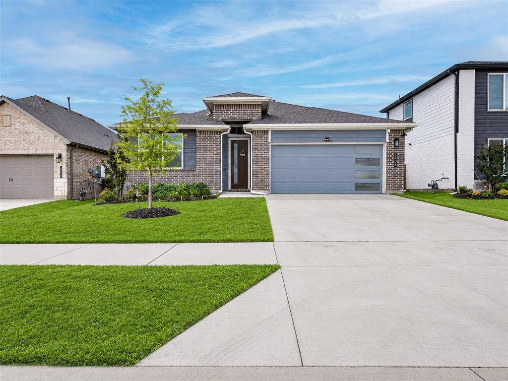 2504 Wren Lane, Denton, TX 76205 Contemporary brick and siding exterior with a dark-tone entry door, an integrated two-car garage with frosted glass panels, and a well-maintained lawn