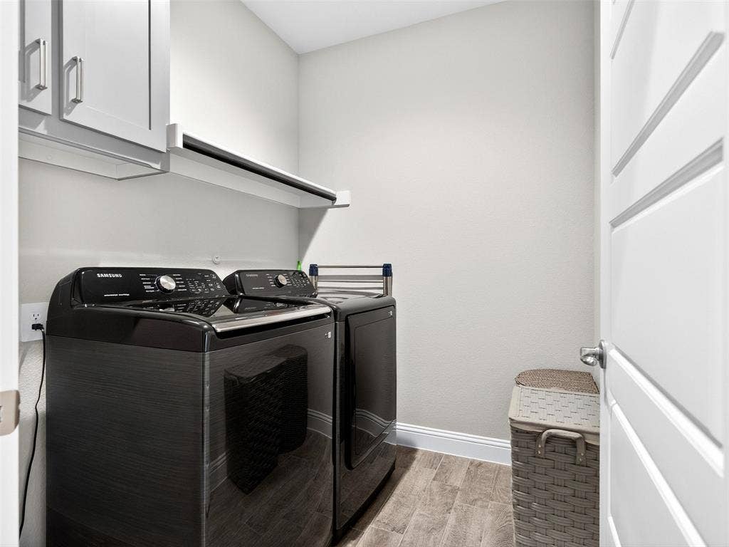 2504 Wren Lane, Denton, TX 76205 Laundry area featuring wood-finish flooring, white cabinetry with brushed nickel hardware, and a wall-mounted shelving unit